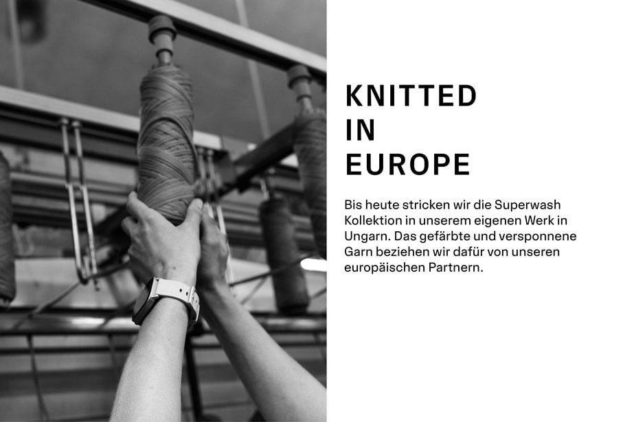 MAERZ Muenchen Merino Superwash Quality Detailbild: eine Hand greift nach einer Wollspule in unserer Fabrik, links steht: Knitted in Europe. Bis heute stricken wir die Superwash Kollektion in unserem eigenen Werk in Ungarn. Das gefärbte und versponnene Garn beziehen wir dafür von unseren europäischen Partnern.
