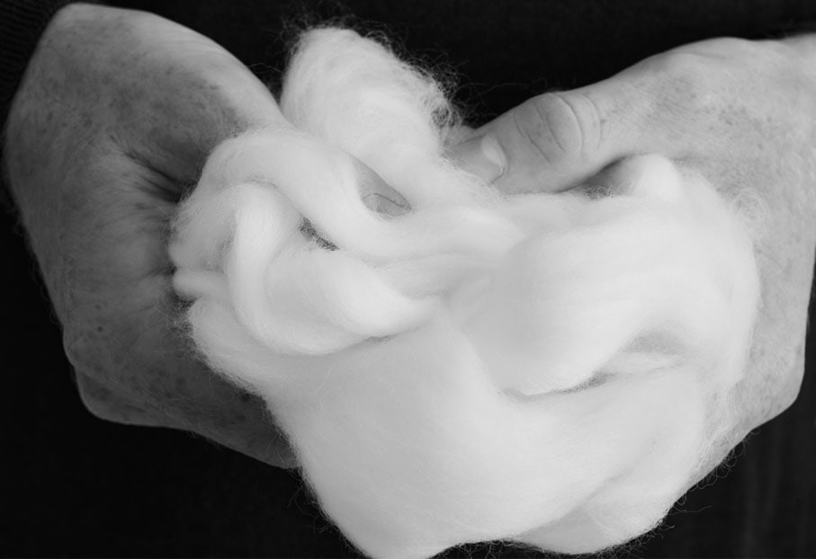 Premium Merino. Detailbild: Hände halten einen Bündel Watte