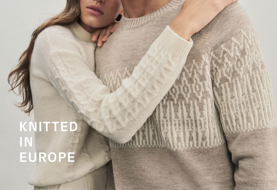Zwei Menschen umarmen sich und tragen dabei Pullover mit einem ausdrucksstarken Jacquard-Muster. Knitted In Europe.