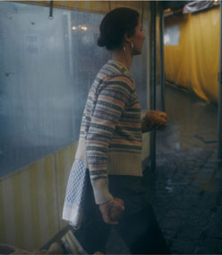 Eine Frau in einer hellen Strickjacke mit traditionellem Muster steht am Caspar Plautz Stand