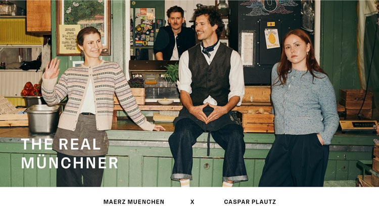 Text: THE REAL MÜNCHNER MAERZ MUENCHEN X CASPAR PLAUTZ. Vier Personen in einem rustikalen Marktladen: links eine Frau in einer hellen Strickjacke mit traditionellem Muster, in der Mitte ein Mann in weißem Hemd, grauen Trachtenweste und Halstuch im Trachtenstil, rechts eine Frau in einer blauen Trachten-Strickjacke. Im Hintergrund steht ein weiterer Mann in einem dunkelblauen Janker hinter der Theke.