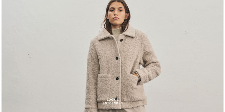 Favourite New Look Frau in beiger Kuscheljacke im Teddylook trägt Rollkragenpullover mit Strickmuster aus 100 % Schurwolle und passende Hose, vor heller Wand.