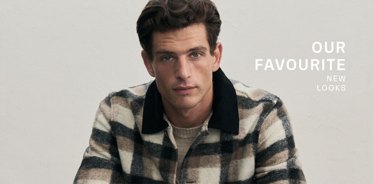 Ein Mann blickt direkt in die Kamera und trägt ein markantes Overshirt mit Karomuster in Navy, Beige und Weiß. Der elegante Umlegekragen aus Cord verleiht dem Look eine edle Note. Text: Favourite New Look
