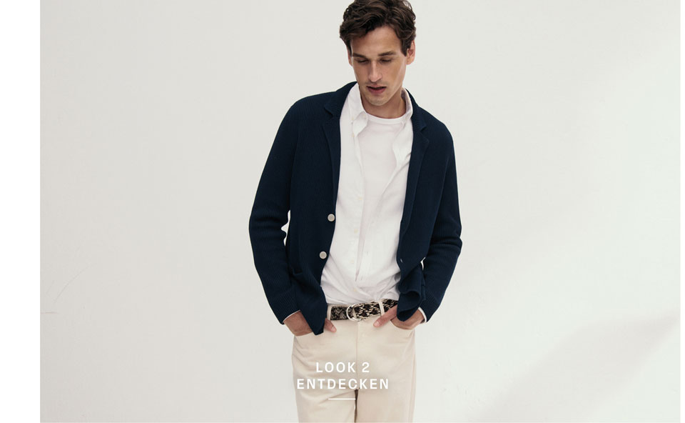 Look 2 entdecken: Mann in dunkelblauer Strickjacke über weißem Hemd und Shirt sowie heller Hose – hochwertige Herren Knitwear für moderne Premium Looks.