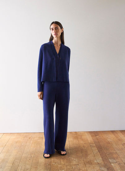 Frau im dunkelblauen Strickset aus Cardigan und Hose, minimalistisch inszeniert für eine ruhige, hochwertige Premium Ästhetik.