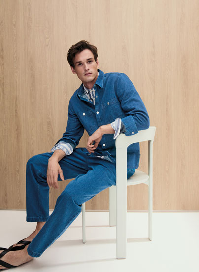 Mann im kompletten Knitted Denim Set aus Jacke und Hose, lässig kombiniert mit Hemd – strukturierte Premium Knitwear in ikonischem Blau.
