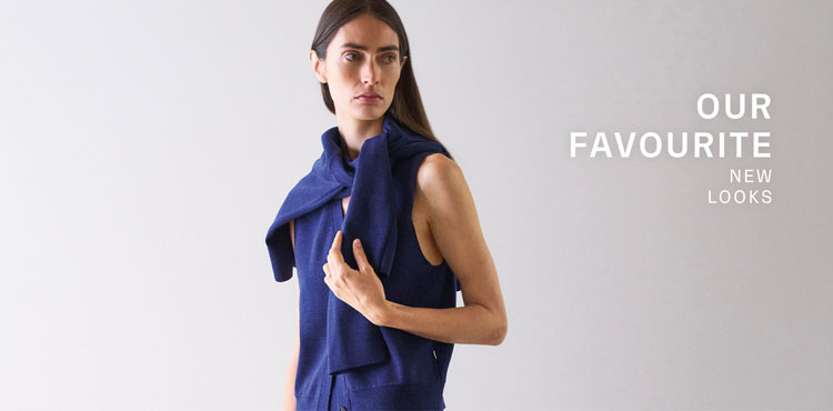 Our Favourite New Looks: Frau in modernem Navy Stricklook mit locker übergeworfenem Pullover, clean inszeniert vor ruhigem Hintergrund für eine zeitlose Premium Ästhetik.