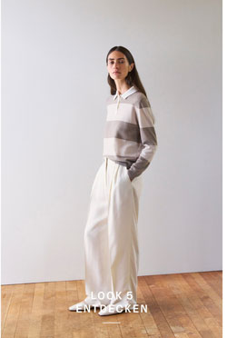 Look 5 entdecken: Frau im gestreiften Strick Polo in soften Naturtönen und weiter Hose, modern und ruhig inszeniert für eine edle Premium Ästhetik.