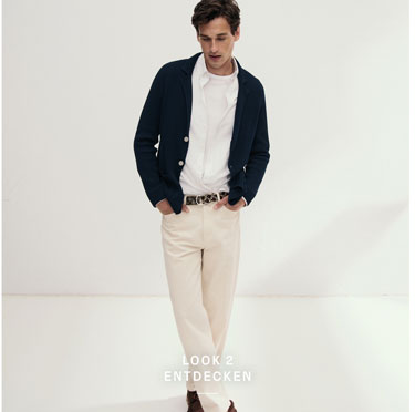 Look 2 entdecken: Mann in dunkelblauer Strickjacke über weißem Hemd und Shirt sowie heller Hose – hochwertige Herren Knitwear für moderne Premium Looks.