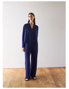 Frau im dunkelblauen Strickset aus Cardigan und Hose, minimalistisch inszeniert für eine ruhige, hochwertige Premium Ästhetik.