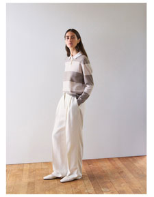 Frau im gestreiften Strick Polo in soften Naturtönen und weiter Hose, modern und ruhig inszeniert für eine edle Premium Ästhetik.