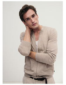 Mann in leichter Strickjacke und weißem Shirt, modern und entspannt inszeniert für eine natürliche, hochwertige Premium Ästhetik.