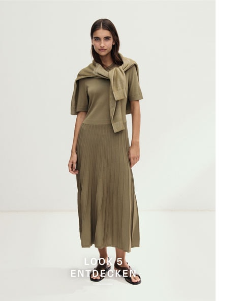 Look 5 entdecken: Our Favourite New Looks. Frau in olivfarbenem Kleid und umgelegter Strickjacke, minimalistisch im Studio inszeniert.