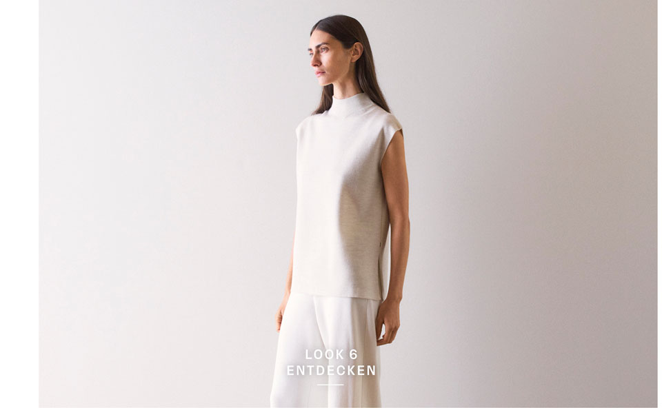 Look 6 entdecken: Our Favourite New Looks. Frau in hellem Strickpullunder und weiter Hose, minimalistisch im Studio inszeniert – hochwertige Knitwear für moderne Premium Looks.