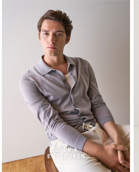 Our Favourite New Looks: Mann in feiner Strickjacke und heller Hosen, lässig im modernen Indoor Setting präsentiert.