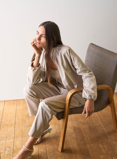Our Favourite New Looks: Frau in heller Strickjacke mit passender Hose, entspannt im Licht eines modernen Wohnraums inszeniert.