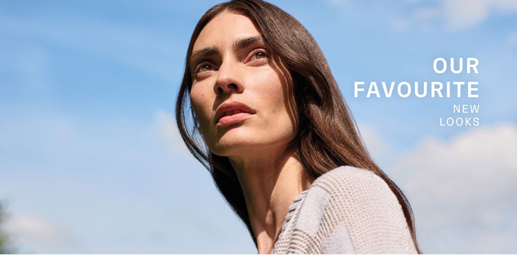 Our Favourite New Look: Frau in heller Strickjacke mit grafischem Muster, ruhig vor blauem Himmel inszeniert.