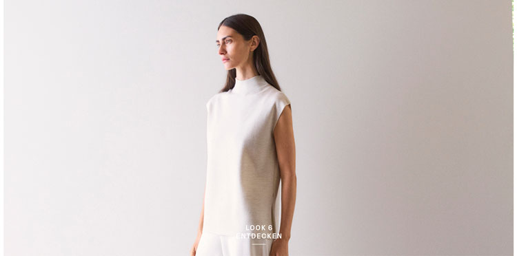 Look 6 entdecken: Our Favourite New Looks. Frau in hellem Strickpullunder und weiter Hose, minimalistisch im Studio inszeniert – hochwertige Knitwear für moderne Premium Looks.