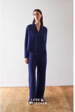 Look 9 entdecken: Our Favourite New Looks. Frau im dunkelblauen Strickset aus Cardigan und Hose, minimalistisch inszeniert für eine ruhige, hochwertige Premium Ästhetik.