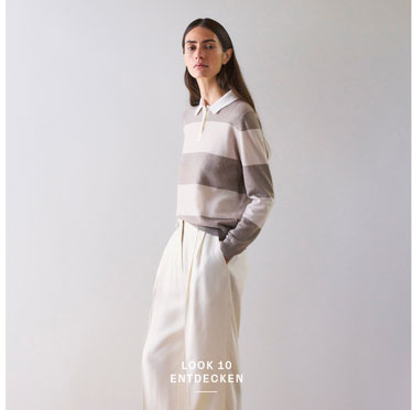 Look 10 entdecken: Our Favourite New Looks. Frau im gestreiften Strick Polo in soften Naturtönen und weiter Hose, modern und ruhig inszeniert für eine edle Premium Ästhetik.