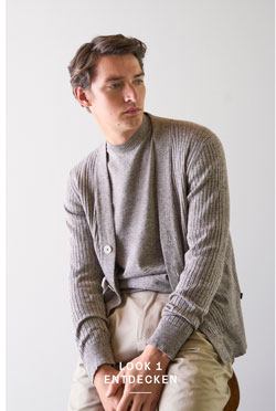 Look 1 entdecken: Our Favourite New Looks. Mann in feiner Strickjacke und heller Hosen, lässig im modernen Indoor Setting präsentiert.