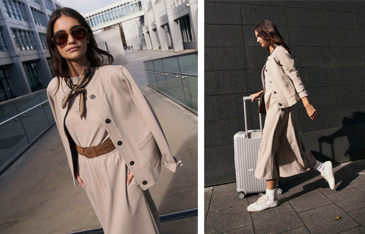 Frau im beigen TO CASUAL Look mit Strickjacke, Kleid und Sneakers, modern und dynamisch unterwegs vor urbaner Architektur.