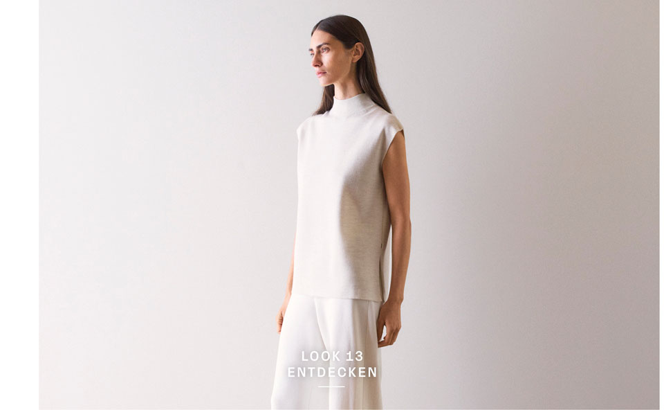 Look 13 entdecken: Our Favourite New Looks. Frau in hellem Strickpullunder und weiter Hose, minimalistisch im Studio inszeniert – hochwertige Knitwear für moderne Premium Looks.