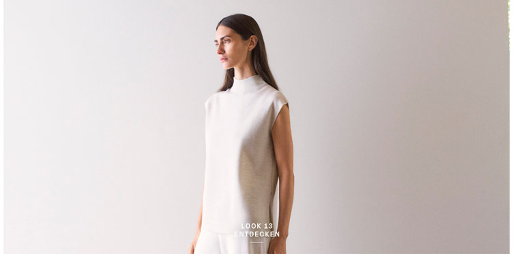 Look 13 entdecken: Our Favourite New Looks. Frau in hellem Strickpullunder und weiter Hose, minimalistisch im Studio inszeniert – hochwertige Knitwear für moderne Premium Looks.