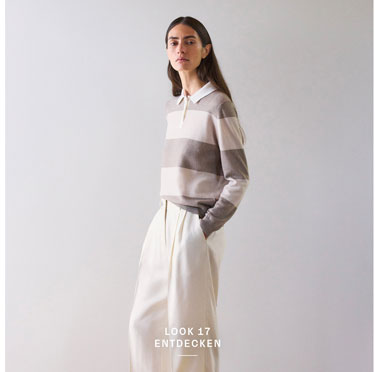 Look 17 entdecken: Our Favourite New Looks. Frau im gestreiften Strick Polo in soften Naturtönen und weiter Hose, modern und ruhig inszeniert für eine edle Premium Ästhetik.