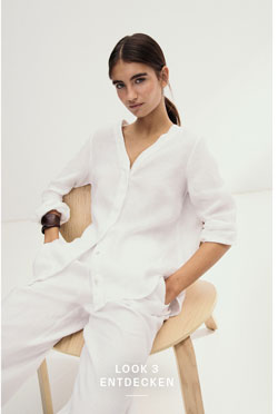 Look 3 entdecken: Our Favourite New Looks: Frau in lockerem weißem Leinen Set aus Bluse und Hose, minimalistisch im Studio auf einem hellen Stuhl inszeniert.