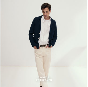 Look 16 entdecken: Mann in dunkelblauer Strickjacke über weißem Hemd und Shirt sowie heller Hose – hochwertige Herren Knitwear für moderne Premium Looks.