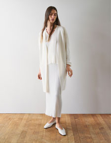 Look 1 entdecken: Our Favourite New Looks: Frau in langem, cremefarbenem Strick Ensemble mit offenem Cardigan, ruhig im Studio vor heller Wand inszeniert, leichte Premium Strickqualität.