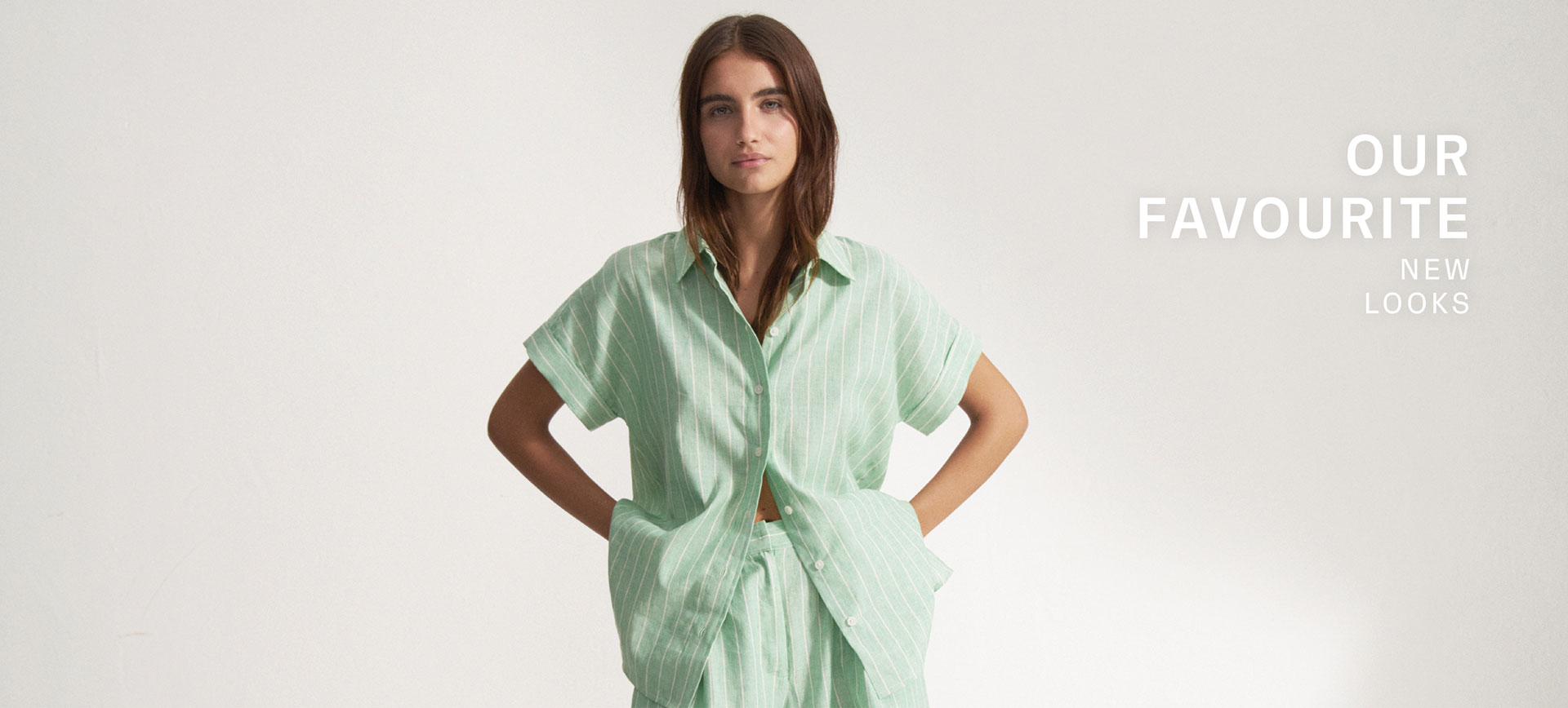 Our Favourite New Looks: Frau im mintfarbenen, gemusterten Sommerhemd mit Midishorts, entspannt auf Stuhl inszeniert – moderner Premium Look zum Nachstylen. Our Favourite New Looks: