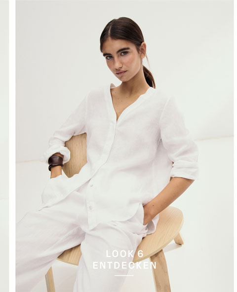Look 6 entdecken: Our Favourite New Looks: Frau in lockerem weißem Leinen Set aus Bluse und Hose, minimalistisch im Studio auf einem hellen Stuhl inszeniert.
