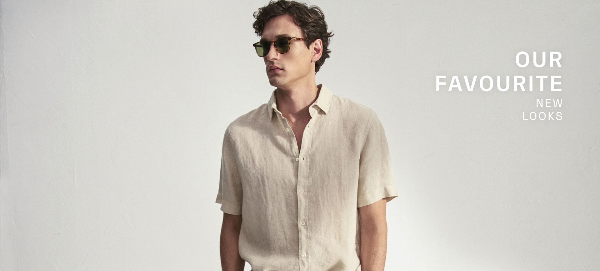 Our Favourite New Looks: Our Favourite New Looks: Mann im hellen Sommerlook aus Leinenhemd und Shorts, modern vor Studiohintergrund inszeniert.