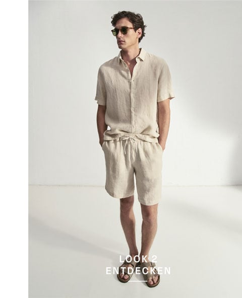 Look 2 entdecken: Our Favourite New Looks: Mann im hellen Sommerlook aus Leinenhemd und Shorts, modern vor Studiohintergrund inszeniert.