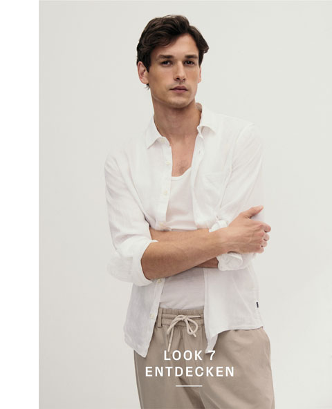Look 7 entdecken: Our Favourite New Looks: Mann im weißen Shirt und offenem Hemd, kombiniert mit beigefarbener Hose, modern im hellen Studio inszeniert.
