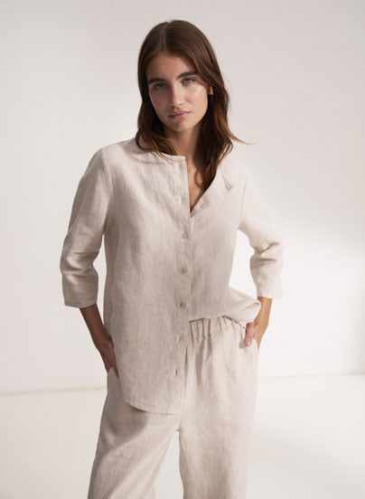 Our Favourite New Looks: Frau im hellen Linen Outfit aus Hemd und Hose, reduziert und ruhig im Studio inszeniert – zeitloser Sommerlook zum Nachstylen.