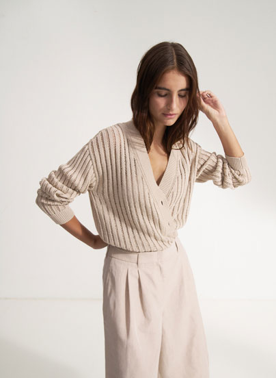 Our Favourite New Looks: Frau in feiner, heller Strickjacke mit Shorts, modern und reduziert inszeniert – eleganter Sommerlook zum Nachstylen.