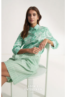 Look 1 entdecken: Our Favourite New Looks: Frau im mintfarbenen, gemusterten Sommerhemd mit Midishorts, entspannt auf Stuhl inszeniert – moderner Premium Look zum Nachstylen.