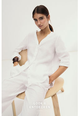 Look 6 entdecken: Our Favourite New Looks: Frau in lockerem weißem Leinen Set aus Bluse und Hose, minimalistisch im Studio auf einem hellen Stuhl inszeniert.