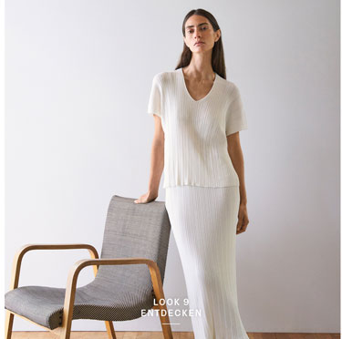 Look 9 entdecken: Our Favourite New Looks: Frau in langem, cremefarbenem Strick Ensemble mit offenem Cardigan, ruhig im Studio vor heller Wand inszeniert, leichte Premium Strickqualität.