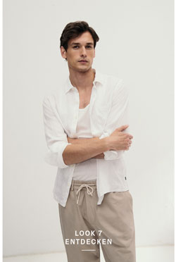Look 7 entdecken: Our Favourite New Looks: Mann im weißen Shirt und offenem Hemd, kombiniert mit beigefarbener Hose, modern im hellen Studio inszeniert.