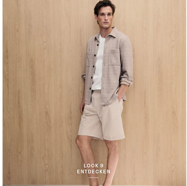 Look 9 entdecken: Our Favourite New Looks: Mann im hellen Sommer Set aus offener Hemdjacke, Shirt und Shorts, lässig vor warmer Holzfläche inszeniert.