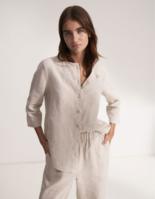 Our Favourite New Looks: Frau im hellen Linen Outfit aus Hemd und Hose, reduziert und ruhig im Studio inszeniert – zeitloser Sommerlook zum Nachstylen.