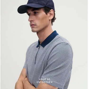 Look 10 entdecken: Our Favourite New Looks: Mann im fein gemusterten Poloshirt und navyfarbener Cap, modern und reduziert im Studio inszeniert.