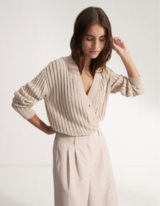 Our Favourite New Looks: Frau in feiner, heller Strickjacke mit Shorts, modern und reduziert inszeniert – eleganter Sommerlook zum Nachstylen.