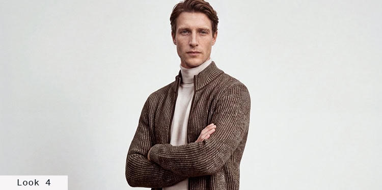 Look 4 English Formality Men: Mann in brauner Strickjacke über hellem Rollkragenpullover vor hellem Hintergrund.