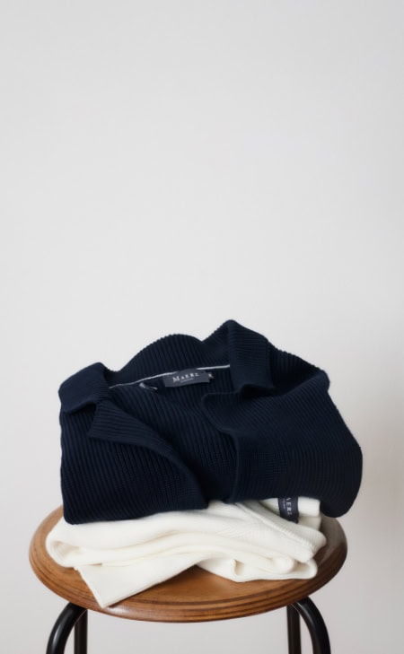 Gefaltete Strickwaren in Dunkelblau und Weiß auf Hocker, mit Text „Knitted in Europe