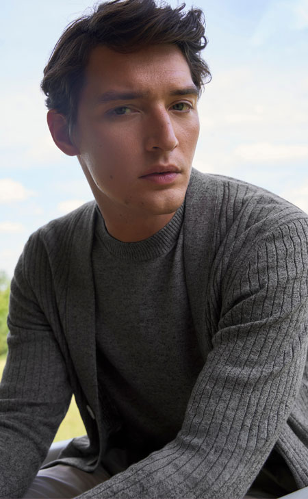 Mann in weichem Cotton‑und‑Linen Strick, ruhig vor hellem Himmel inszeniert – moderne Naturmaterialien für zeitlose Premium‑Looks.